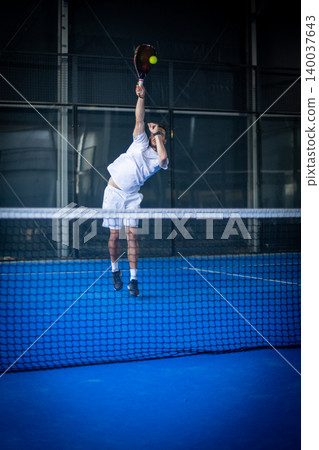 Man playing padel tennis indoor Man playing padel tennis indoor 140037643