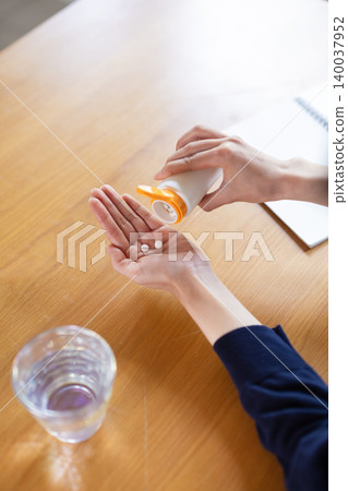 特寫鏡頭拍攝一位女士從藥瓶中取出藥片時的手。 140037952