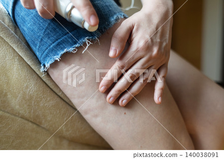 Woman applying anti-cellulite cream from a dispenser bottle onto her thigh skin. Body care routine, weight loss treatment and female lipodystrophy problem concept. 140038091
