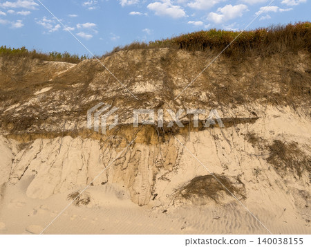 Exposed layers of sandy soil and vegetation on a coastal dune Exposed layers of sandy soil and vegetation on a coastal dune 140038155
