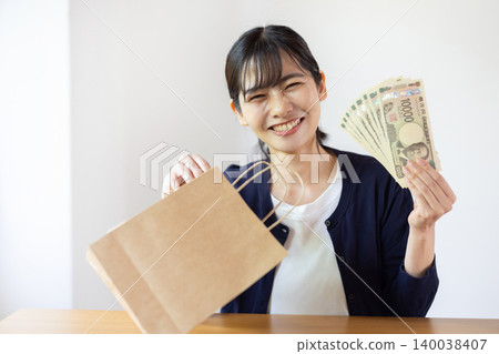 A young Japanese woman smiles as she takes a 10,000 yen bill out of a paper bag in a brightly lit room. A young Japanese woman smiles as she takes a 10,000 yen bill out of a paper bag in a brightly lit room. 140038407