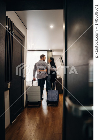 Couple embracing in hotel room doorway with luggage, modern decor, wooden floor, and bright lighting creating a welcoming atmosphere for travelers Couple embracing in hotel room doorway with luggage, modern decor, wooden floor, and bright lighting creating a welcoming atmosphere for travelers 140039071