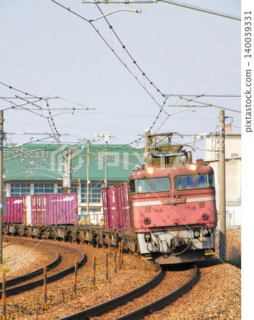 一列由日本國鐵塗裝的 EF81 型電力機車(粉紅色機車)牽引的貨運列車,在原北陸本線上有力地轉彎。 一列由日本國鐵塗裝的 EF81 型電力機車(粉紅色機車)牽引的貨運列車,在原北陸本線上有力地轉彎。 140039331