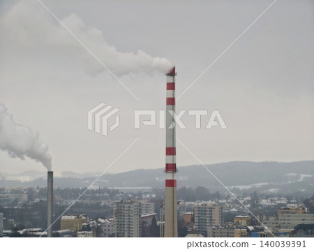 Twin industrial chimneys release smoke over residential areas during gloomy winter weather Twin industrial chimneys release smoke over residential areas during gloomy winter weather 140039391