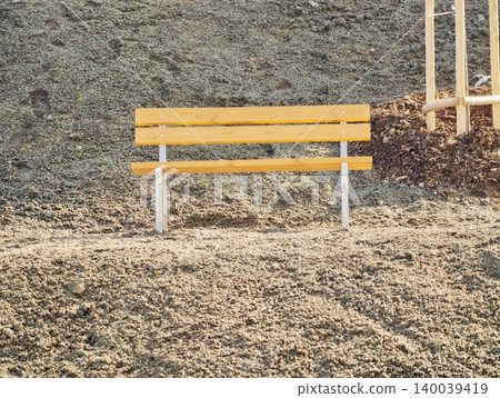 Quiet park bench under bright sunlight. Calm outdoor setting with bright bench and seasonal autumn tones Quiet park bench under bright sunlight. Calm outdoor setting with bright bench and seasonal autumn tones 140039419