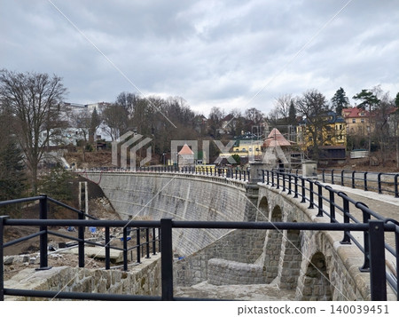 Landscape with dam and sky. Cinematic image of curved dam railings with textured stone and stormy sky Landscape with dam and sky. Cinematic image of curved dam railings with textured stone and stormy sky 140039451
