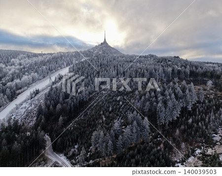 Snowy mountain top with communication structures overlooks frosted woodland and ski terrains from above Snowy mountain top with communication structures overlooks frosted woodland and ski terrains from above 140039503