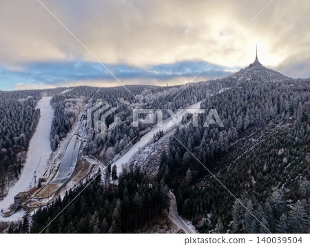 Clear winter sky casts light over frosted slopes and dense pine forests with open ski runs Clear winter sky casts light over frosted slopes and dense pine forests with open ski runs 140039504