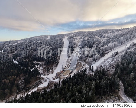 Tranquil alpine resort scene with frosted trees and winding mountain road under overcast sky 140039505
