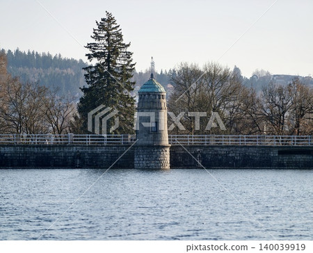Idyllic setting featuring dam path surrounded by lush forestry and peaceful water reflections Idyllic setting featuring dam path surrounded by lush forestry and peaceful water reflections 140039919