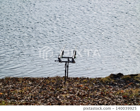 Quiet lakeside angler with rod. Tranquil lakeshore scene showcasing solitary fisherman waiting patiently 140039925