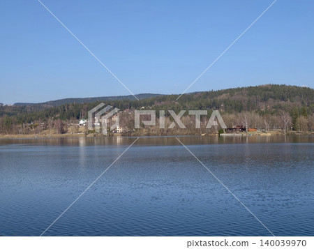 Expansive water and mountain vista. Calm waters reflect sky and distant mountain range scenery Expansive water and mountain vista. Calm waters reflect sky and distant mountain range scenery 140039970