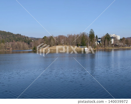 Peaceful island setting featuring secluded dock. Idyllic island scene with tranquil waters and towering tree Peaceful island setting featuring secluded dock. Idyllic island scene with tranquil waters and towering tree 140039972
