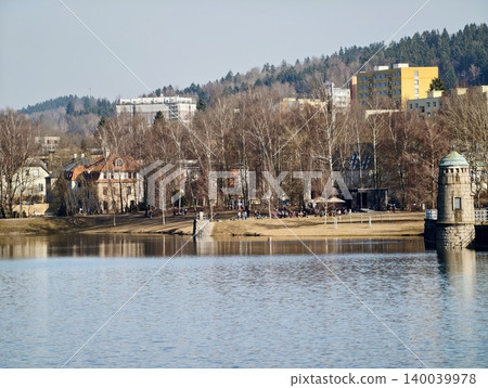 Vibrant riverside architecture displaying mirror images on calm water surfaces with natural and city features Vibrant riverside architecture displaying mirror images on calm water surfaces with natural and city features 140039978