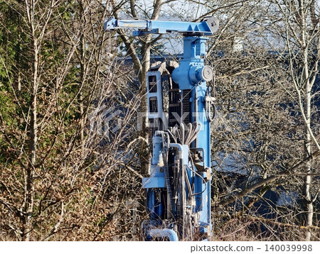 Weathered metal pulley amidst leafless trees. Late winter scene of derelict utility tower with shadows Weathered metal pulley amidst leafless trees. Late winter scene of derelict utility tower with shadows 140039998