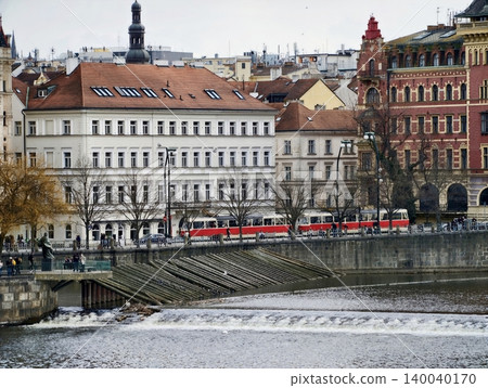 Urban tram scene. European cityscape featuring tram crossing over river and historic architecture Urban tram scene. European cityscape featuring tram crossing over river and historic architecture 140040170
