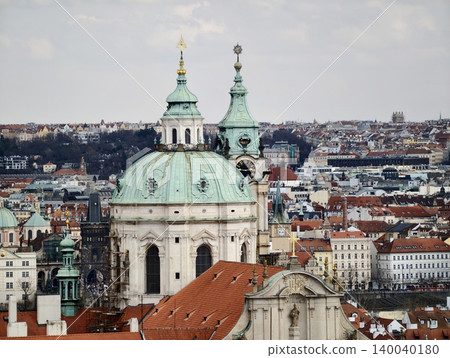 Architectural elements adorn layered city skyline. Sunlit view of ancient bell towers and tiled rooftops Architectural elements adorn layered city skyline. Sunlit view of ancient bell towers and tiled rooftops 140040180