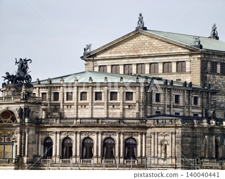 Elegant historic facade. Stylish neoclassical building showcasing sculptures and decorative elements Elegant historic facade. Stylish neoclassical building showcasing sculptures and decorative elements 140040441