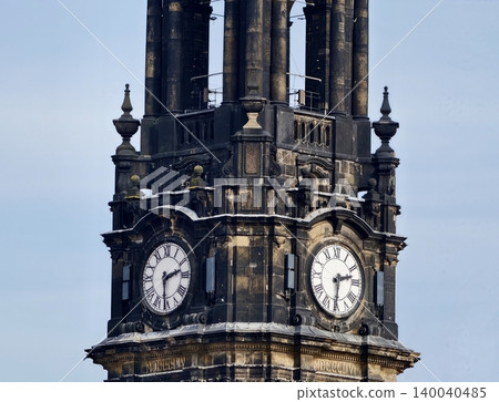 Elaborate clock faces featuring dual dials and antique metallic hands amidst weathered stone architecture Elaborate clock faces featuring dual dials and antique metallic hands amidst weathered stone architecture 140040485