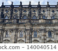 Facade of structure exhibiting historic architectural features and textured stone workmanship across surface 140040514