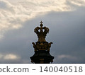 Intricate crown sculpture emphasizing baroque artistry with gilded details and atmospheric cloud patterns 140040518