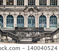 Decorative and weathered stone staircase ascends to impressive symmetrical front facade with detailed carvings 140040524