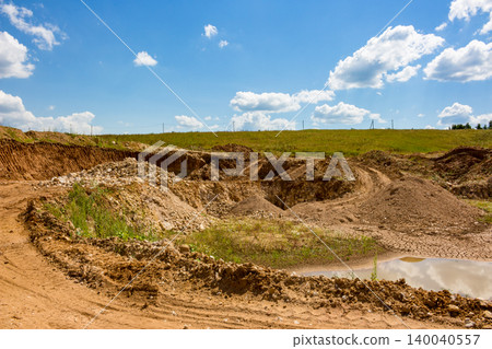 Expansive open-pit quarry under a bright sky, showcasing excavated earth, dirt mounds, and vehicle tracks. A raw, industrial landscape with natural elements Expansive open-pit quarry under a bright sky, showcasing excavated earth, dirt mounds, and vehicle tracks. A raw, industrial landscape with natural elements 140040557