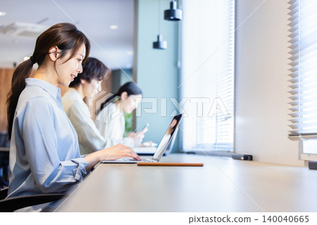 People working at the counter seats in a coworking space. People working at the counter seats in a coworking space. 140040665