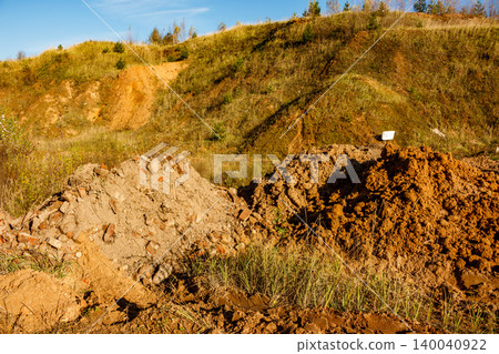 Two distinct piles of earth, one with brick bits, dominate this construction or landfill site. A grassy hill and blue sky form the backdrop Two distinct piles of earth, one with brick bits, dominate this construction or landfill site. A grassy hill and blue sky form the backdrop 140040922
