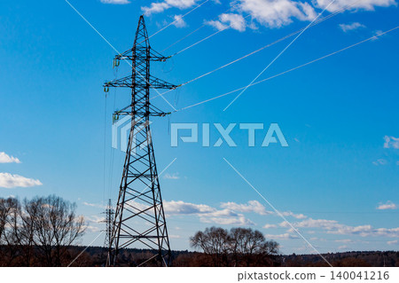 Towering power pylon stands proudly against a bright blue sky with wispy clouds. Its high-voltage lines deliver energy across a serene, bare landscape Towering power pylon stands proudly against a bright blue sky with wispy clouds. Its high-voltage lines deliver energy across a serene, bare landscape 140041216