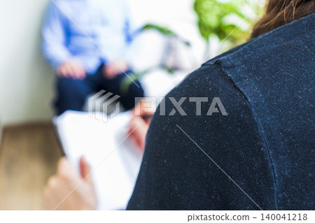 Close Up of Psychologist Hand Taking Notes During Therapy Session with Client 140041218