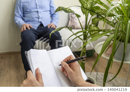 Close Up of Psychologist Hand Taking Notes During Therapy Session with Client 140041219