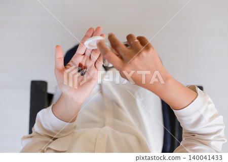 Hands open small container. Fingers delicately handle product. Person wears light-colored shirt. Simple background, clean and bright. Ideal for beauty or health product ads Hands open small container. Fingers delicately handle product. Person wears light-colored shirt. Simple background, clean and bright. Ideal for beauty or health product ads 140041433
