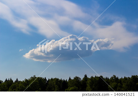 Single fluffy cumulus cloud floats in a vibrant azure sky above a lush green forest line, creating a peaceful atmospheric scenery on a bright sunny summer day Single fluffy cumulus cloud floats in a vibrant azure sky above a lush green forest line, creating a peaceful atmospheric scenery on a bright sunny summer day 140041521