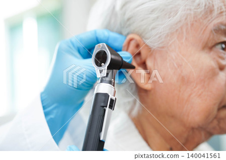 Otolaryngologist or ENT physician doctor examining senior patient ear with otoscope, hearing loss problem. Otolaryngologist or ENT physician doctor examining senior patient ear with otoscope, hearing loss problem. 140041561