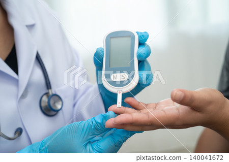 Doctor check diabetes from finger blood sugar level with digital glucose monitor measure and test stripe. Doctor check diabetes from finger blood sugar level with digital glucose monitor measure and test stripe. 140041672