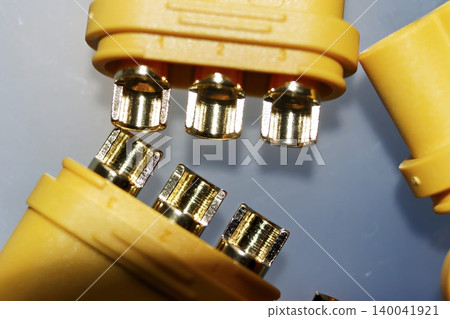 Close-up of bright yellow MR60 connectors, showcasing their shiny gold-plated pins for high-power electric motor connections. Essential for RC and EV power systems Close-up of bright yellow MR60 connectors, showcasing their shiny gold-plated pins for high-power electric motor connections. Essential for RC and EV power systems 140041921