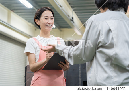 Middle-aged women having a meeting in a warehouse Middle-aged women having a meeting in a warehouse 140041951