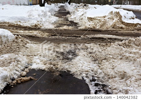Dirty urban winter sidewalk, partially cleared, with grimy brown snowbanks and slush. Realistic city snow removal aftermath Dirty urban winter sidewalk, partially cleared, with grimy brown snowbanks and slush. Realistic city snow removal aftermath 140042382
