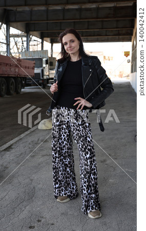 A fashionable look. A beautiful young brunette in a leather jacket and leopard-print pants. A fashionable look. A beautiful young brunette in a leather jacket and leopard-print pants. 140042412