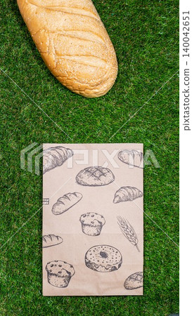 Freshly baked bread and crumpled paper bag on a grass background .Top view. 140042651