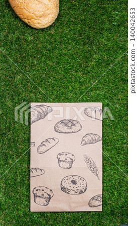 Freshly baked bread and crumpled paper bag on a grass background .Top view. Freshly baked bread and crumpled paper bag on a grass background .Top view. 140042653