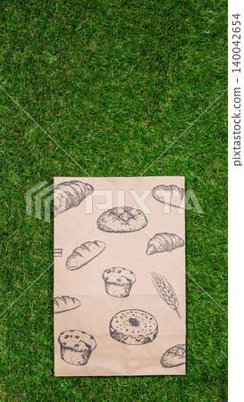 Freshly baked bread and crumpled paper bag on a grass background .Top view. Freshly baked bread and crumpled paper bag on a grass background .Top view. 140042654