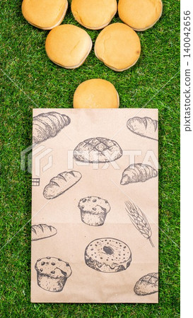 Freshly baked bread and crumpled paper bag on a grass background .Top view. 140042656