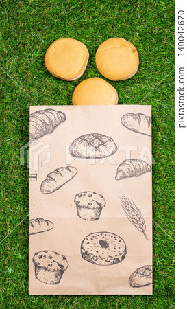 Freshly baked bread and crumpled paper bag on a grass background .Top view. 140042670