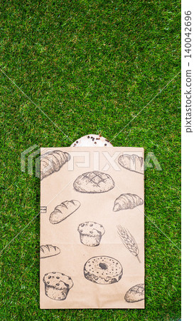 Freshly baked donuts and crumpled paper bag on a grass background .Top view. 140042696