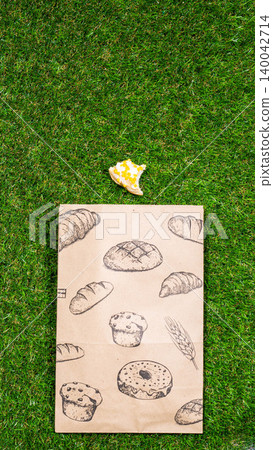 Freshly baked donuts and crumpled paper bag on a grass background .Top view. 140042714
