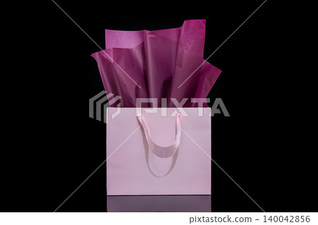 Craft paper gift bag with tissue paper isolated on a black background Craft paper gift bag with tissue paper isolated on a black background 140042856