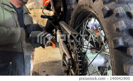 Professional mechanic repairing detail of motorcycle at workplace. Male repairer fixing moto at workshop. Adult repairman mending vehicle at garage. Concept of maintenance service. Slow motion Professional mechanic repairing detail of motorcycle at workplace. Male repairer fixing moto at workshop. Adult repairman mending vehicle at garage. Concept of maintenance service. Slow motion 140042900