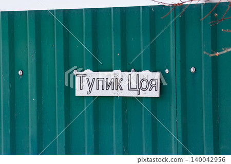 Unique Tsoi's Dead End street sign on a rustic green fence, hinting at a distinct Russian suburban vibe in winter: Kaluga region, Russia 140042956